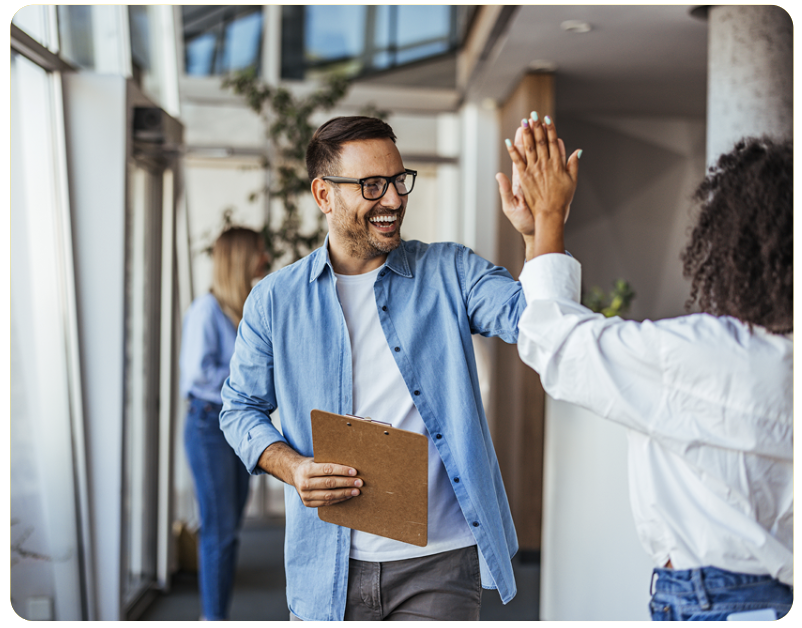 Zwei Mitarbeitende geben sich ein High-Five im modernen Büro – symbolisch für erfolgreiche Teamarbeit, digitale Zusammenarbeit und positive Unternehmenskultur.